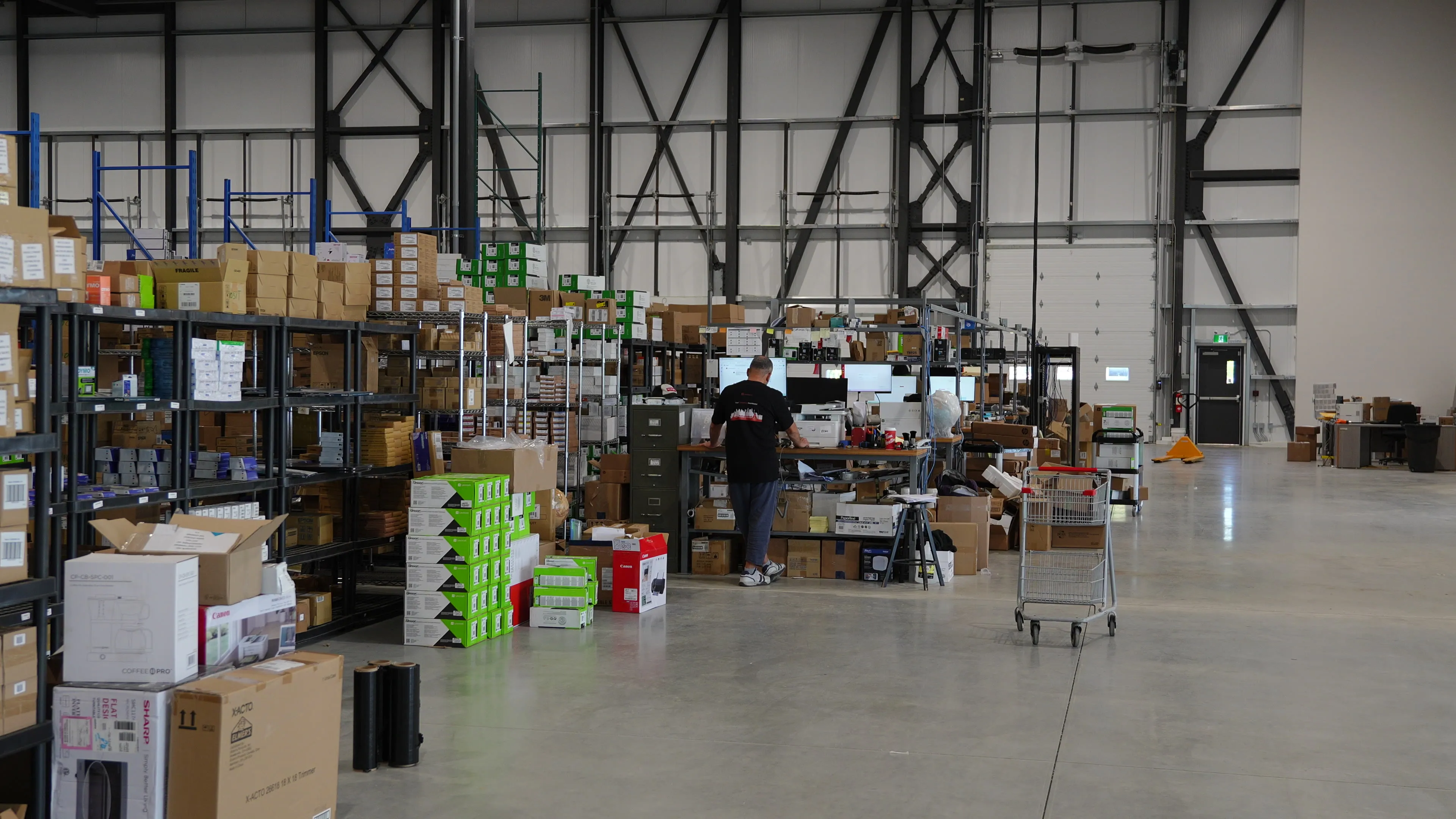 A person working at a workstation among shelving and products in Randmar’s warehouse