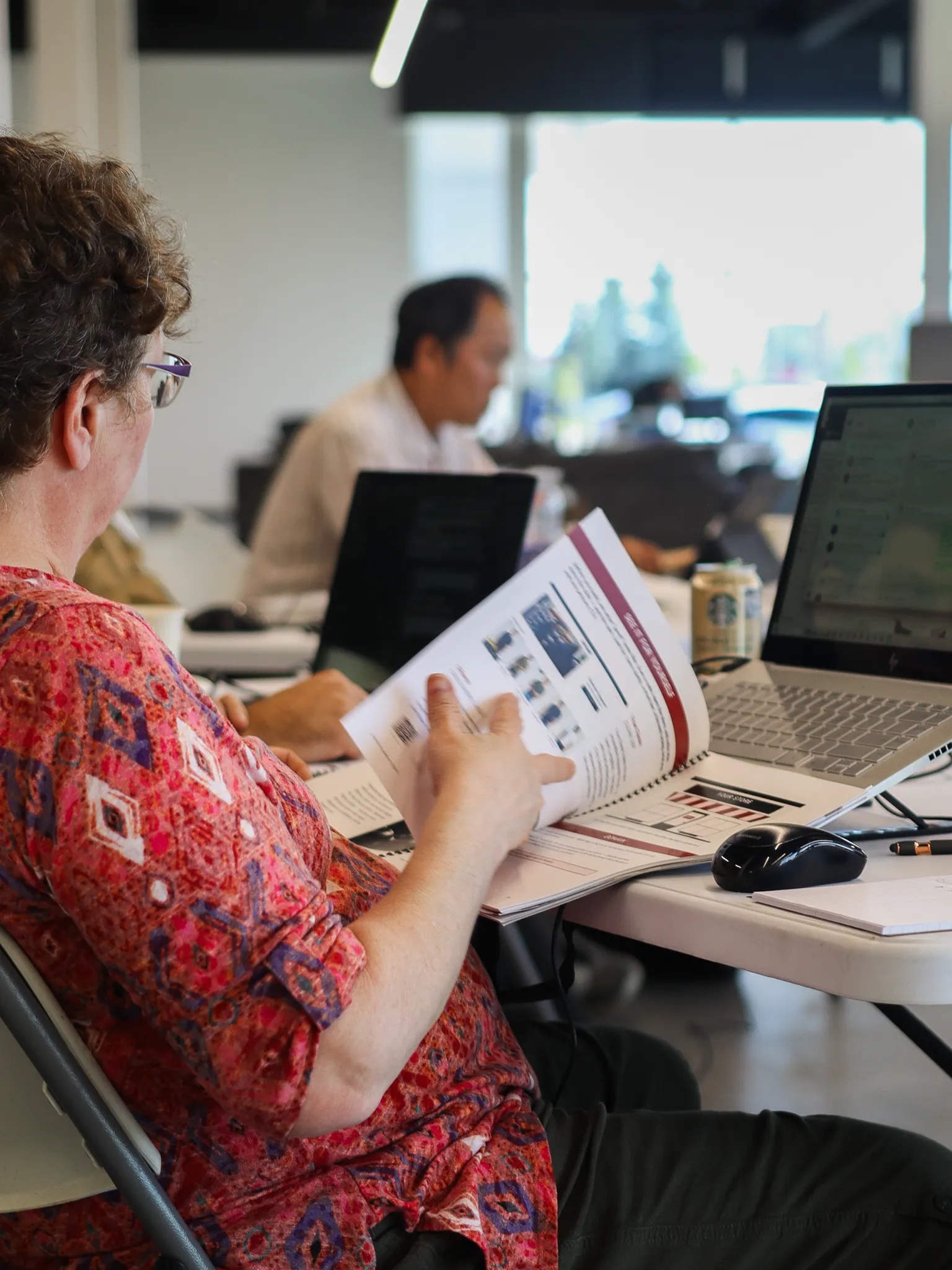 A participant reviewing printed material beside a laptop at a Randmar conference