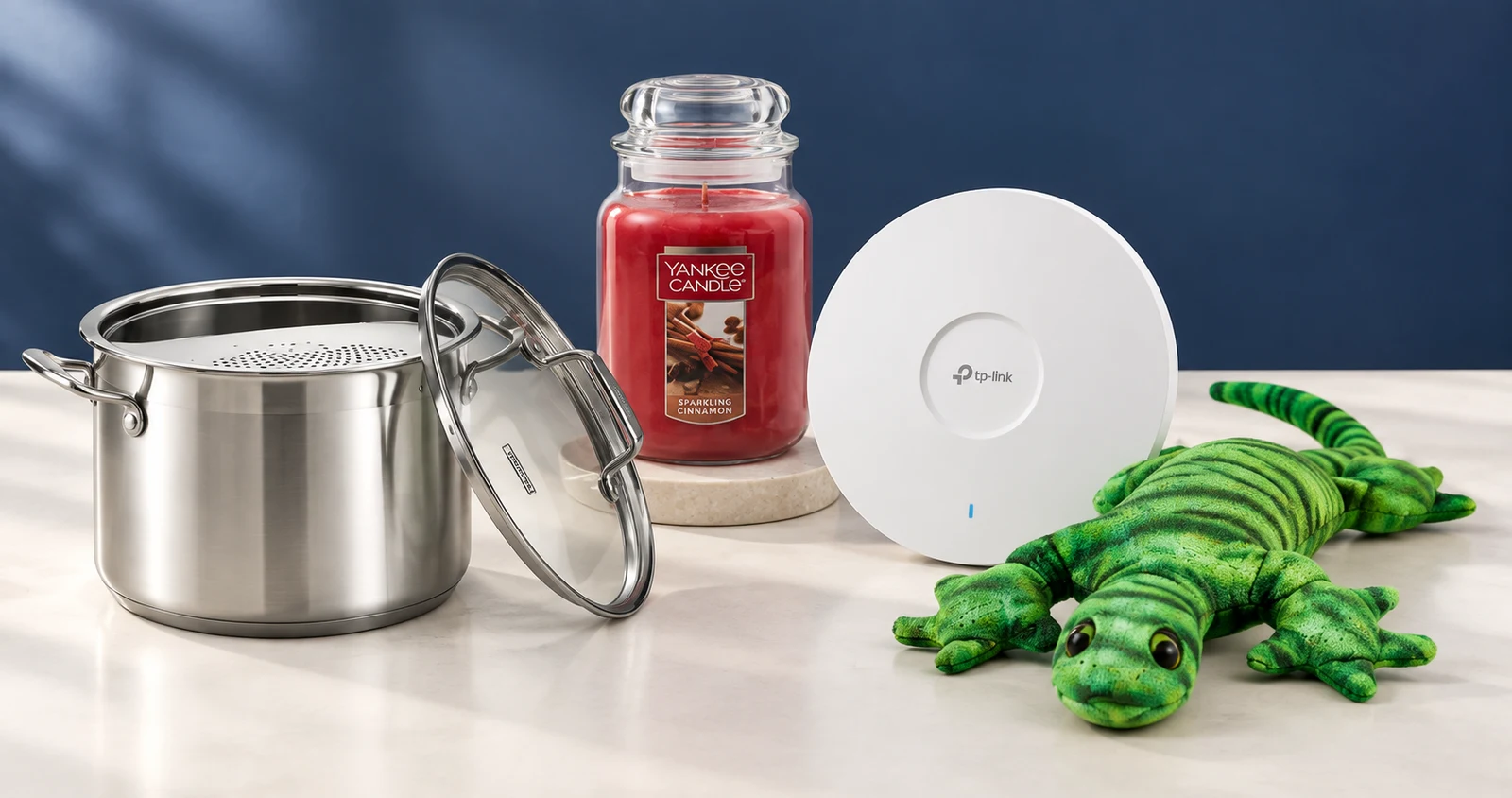 Generated studio composition based on existing imagery of Tramontina cookware, a Yankee Candle jar, TP-Link networking equipment and fdmt weighted plush